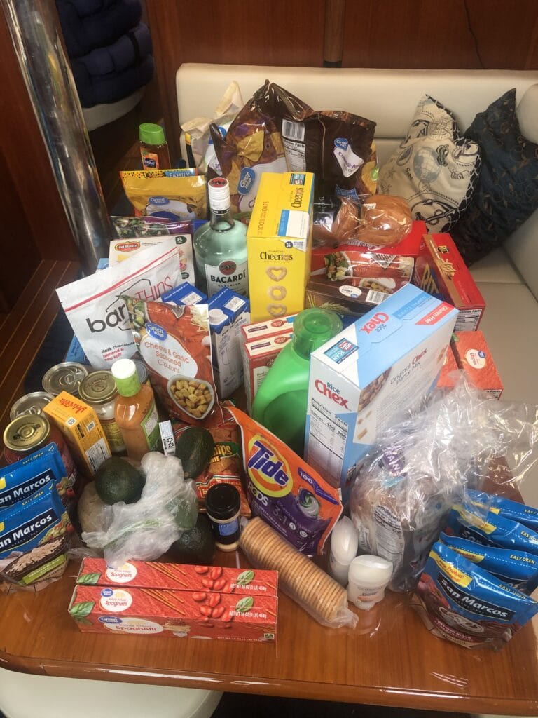 Photo of all the food we bought sitting on our large table in the salon. Items include Cheerios, crackers, pasta, laundry detergent and a bottle of rum hidden in there. Stocking up on food is one of the punchlist items before sailing away.