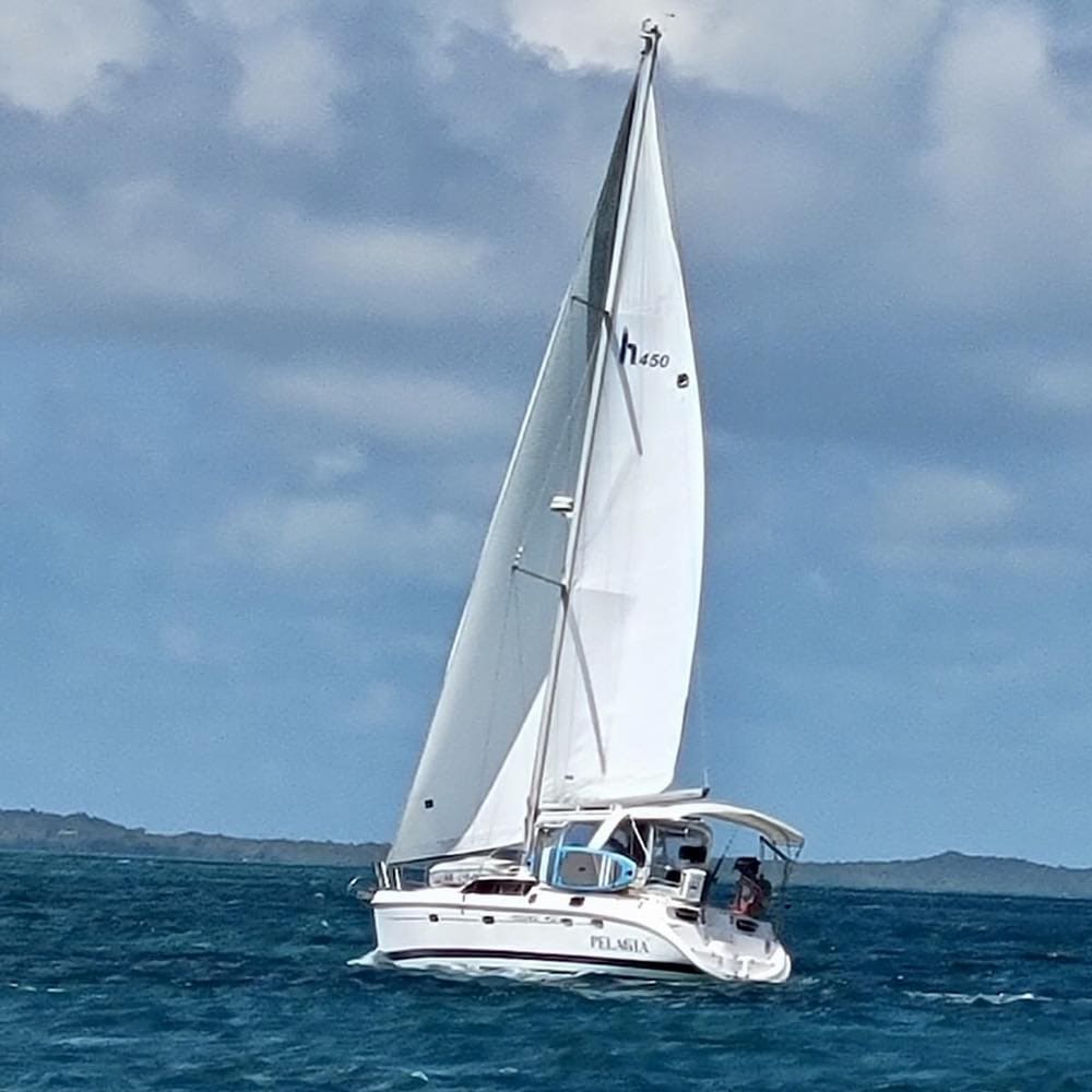 Photo of our sailboat sailing in the Bahamas in blue water and clear skies after reaching our 6 year financial plan to sail away and retire early.