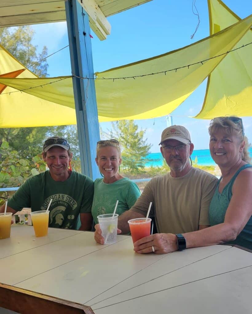 Scott, me, and our friends Daryl and Michele from sail vessel Alaina at the bar at the Beach Club, each with a drink in our hands. There is yellow canvas over us for shade and Scott and I are wearing our Michigan State shirts for ST. Patrick's Day. The only day I can get Scott to wear Michigan State. Go Green!