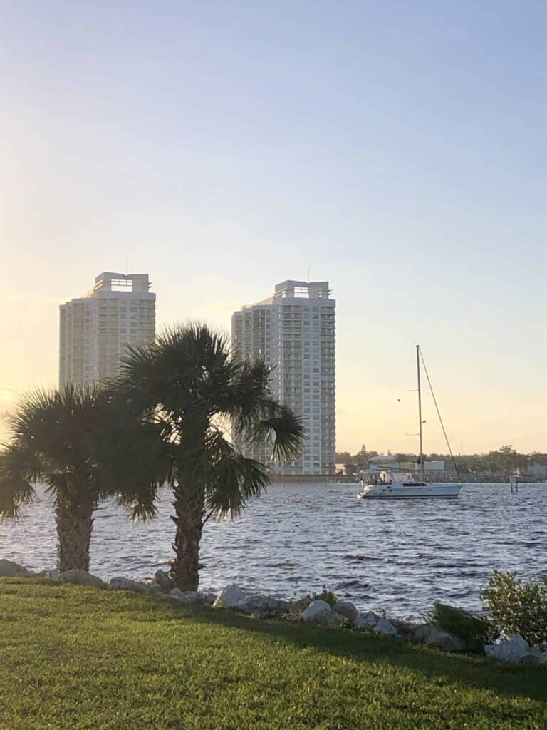 Pelagia anchored just north of the Seabreeze Bridges in Daytona. There are two tall condo tours in the background and two palm trees on the shoreline in the foreground. We are the only boat anchored here at this time just east of the Florida ICW.