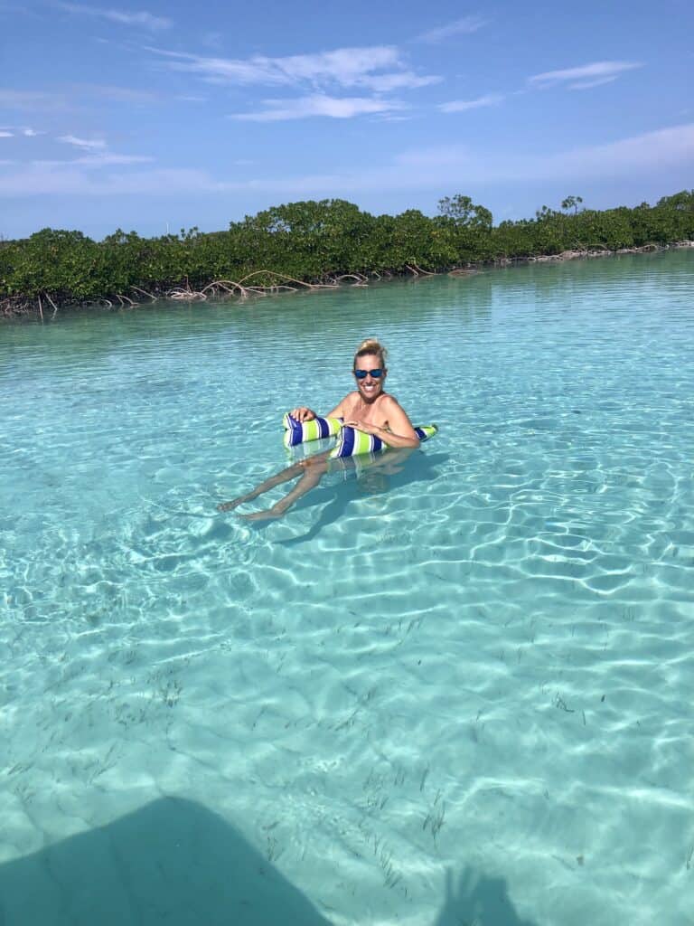 I am floating on my floatie in the crystal clear water in the mangrove river on Shroud Cay