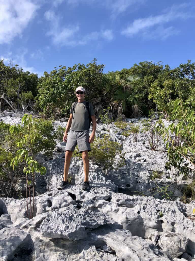 Scott hiking on the rocky terrain on Warderick Wells on a sunny day.
