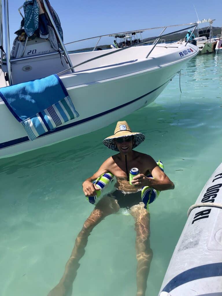 Scott floating in the water with a big straw hat on in the mangrove waters in La Parguera