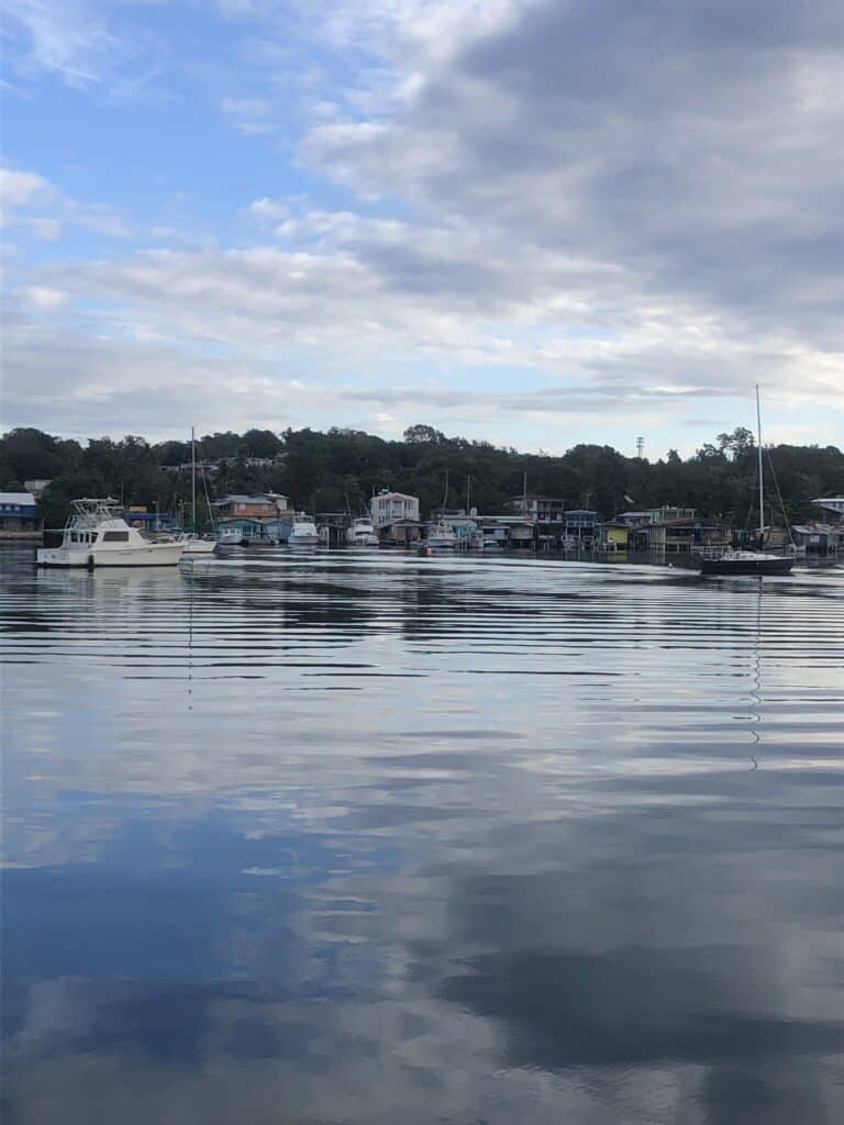 The flat calm anchorage in Puerto Real with a few boats anchored and homes and restaurants along the coastline