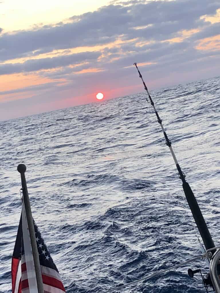 The sun setting during a very rolly passage to Culebra. The sun is pink along the horizon with clouds in front of the orange sky.