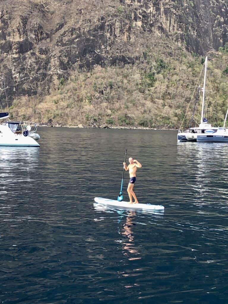 Scott is acting silly flexing on the paddleboard with one of the Piton mountains behind him.