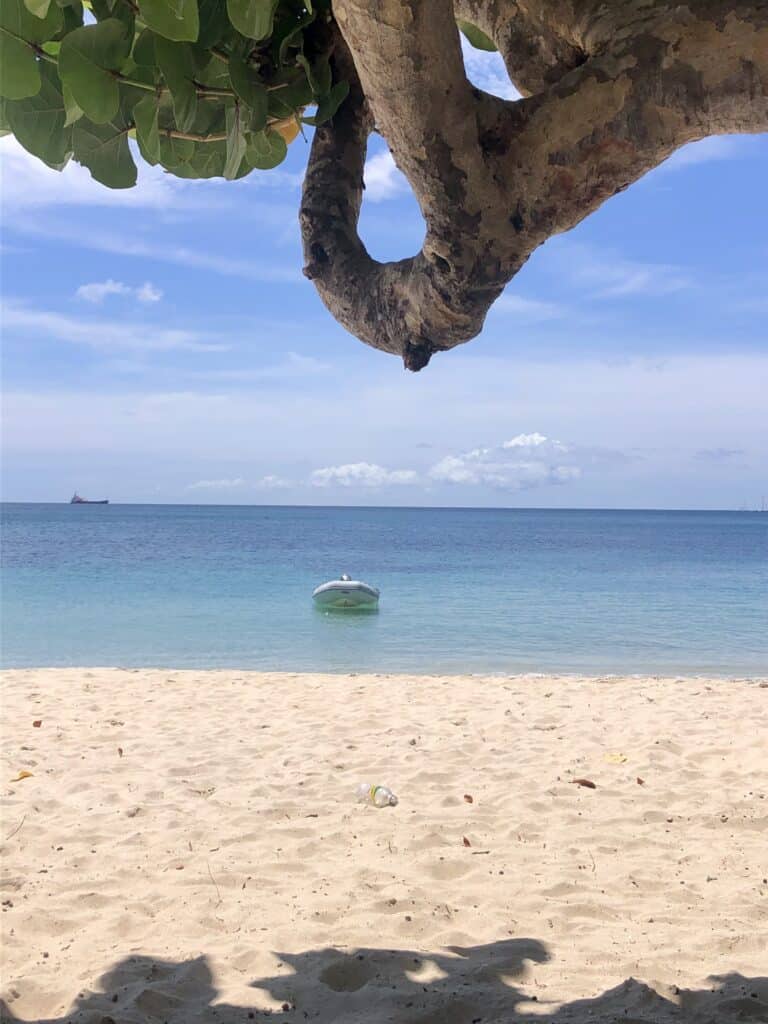 Our dinghy is anchored in the crystal clear waters on a beautiful sunny day at Grand Anse Beach in Grenada.