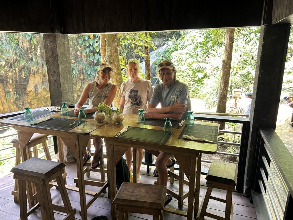 Me, Winnie and Scott are at our table at Wild Orchid with Annandale Waterfalls behind us. There is lush green rain forest surrounding us.