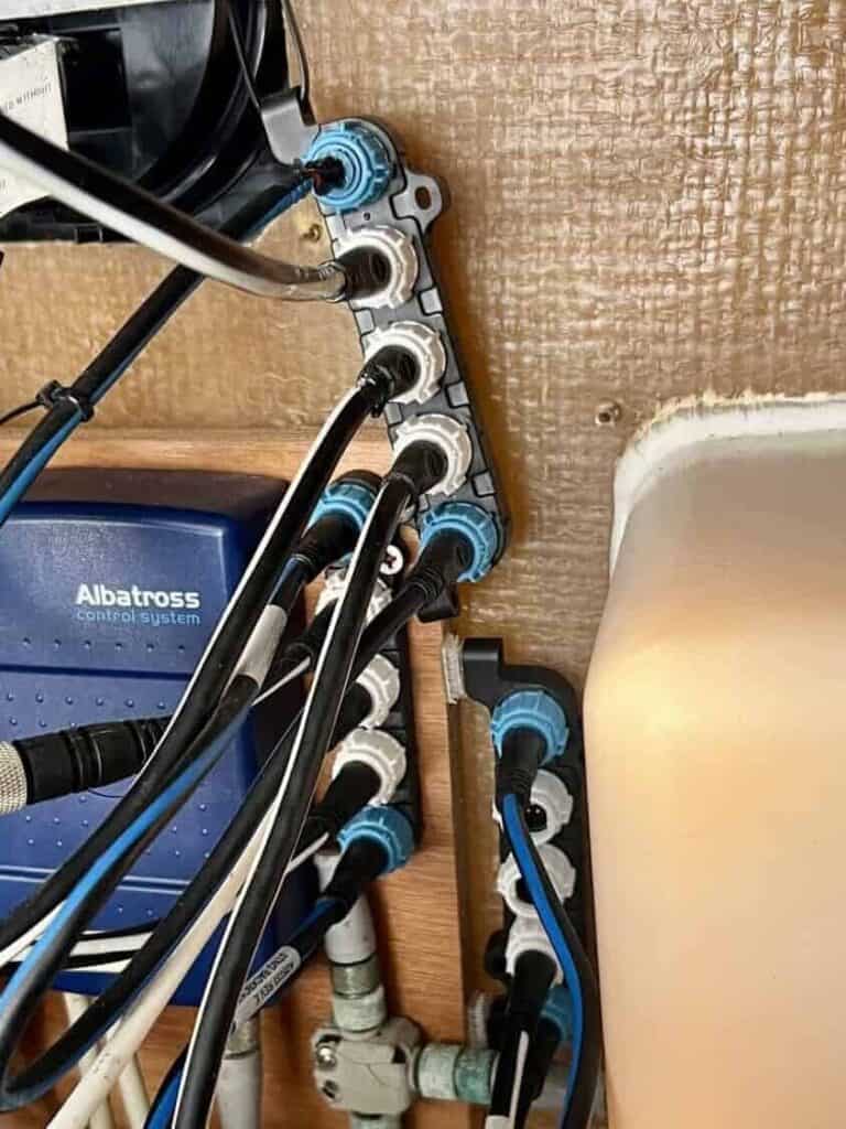 Close up of three Raymarine connector blocks mounted behind the helm with multiple network cables attached. A third connector block was added to create an open port for connecting the DataHub Pro to the boats Raymarine system.